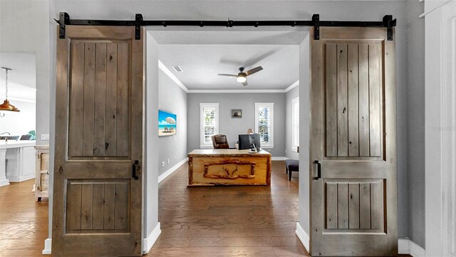 foyer with ornamental molding, baseboards, ceiling fan, a barn door, and hardwood / wood-style flooring