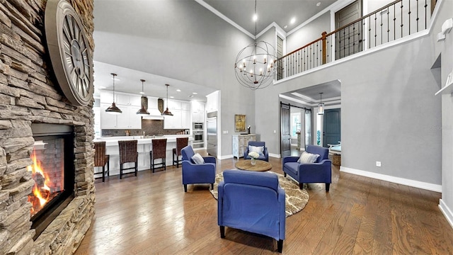 living room with crown molding, a fireplace, dark wood-style floors, and a notable chandelier