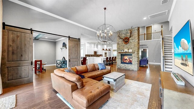 living area featuring visible vents, a barn door, baseboards, and wood finished floors