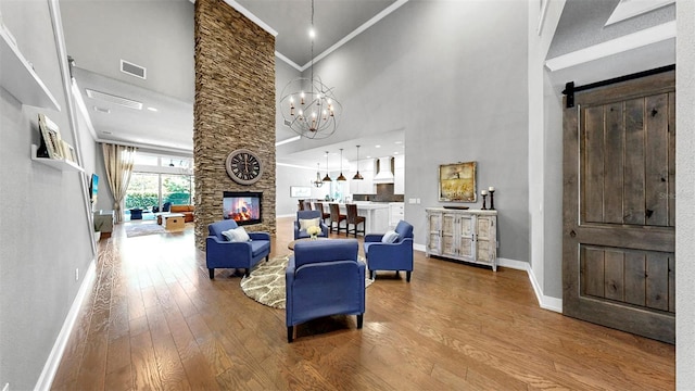 interior space with visible vents, baseboards, a high ceiling, hardwood / wood-style flooring, and a notable chandelier