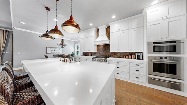 kitchen featuring a kitchen breakfast bar, light countertops, custom range hood, appliances with stainless steel finishes, and a warming drawer