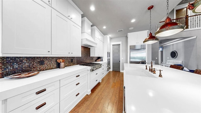 kitchen featuring recessed lighting, custom range hood, a sink, light wood finished floors, and stainless steel appliances