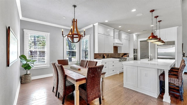 dining area with light wood-type flooring, baseboards, a notable chandelier, ornamental molding, and recessed lighting