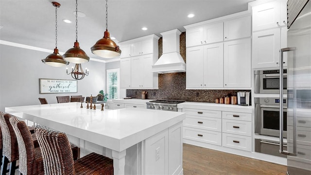 kitchen featuring custom exhaust hood, wood finished floors, a breakfast bar, stainless steel oven, and recessed lighting