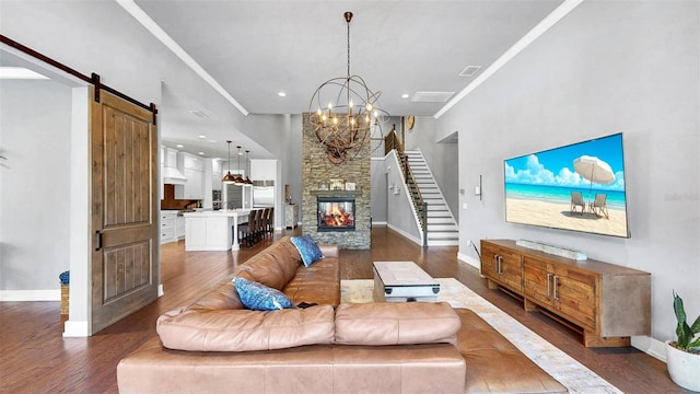 living room featuring a notable chandelier, a barn door, baseboards, wood finished floors, and visible vents