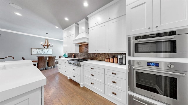 kitchen with an inviting chandelier, recessed lighting, stainless steel gas stovetop, custom range hood, and tasteful backsplash