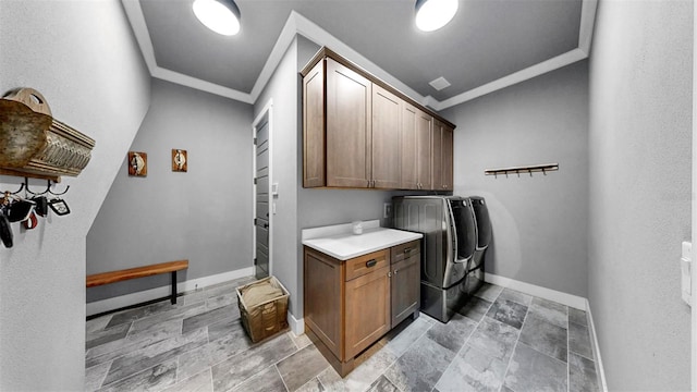 laundry area featuring ornamental molding, baseboards, stone finish flooring, cabinet space, and independent washer and dryer
