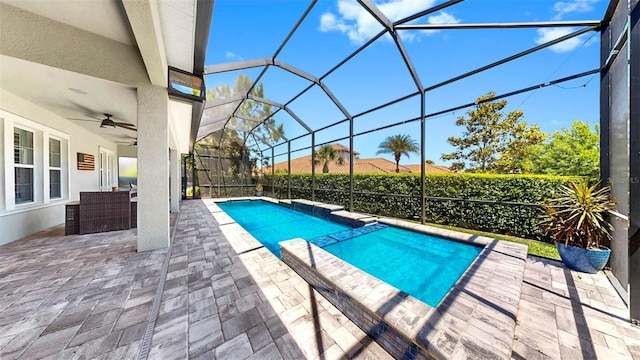 view of swimming pool featuring glass enclosure, a patio, ceiling fan, and a pool with connected hot tub