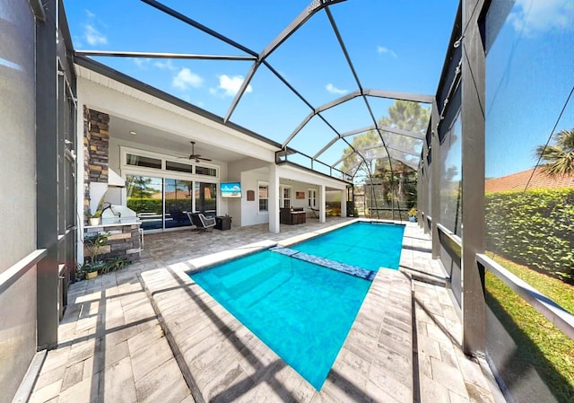 view of pool with area for grilling, ceiling fan, a pool with connected hot tub, glass enclosure, and a patio