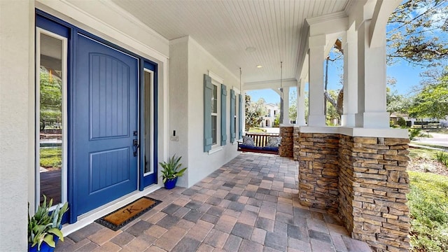 doorway to property with a porch and stucco siding