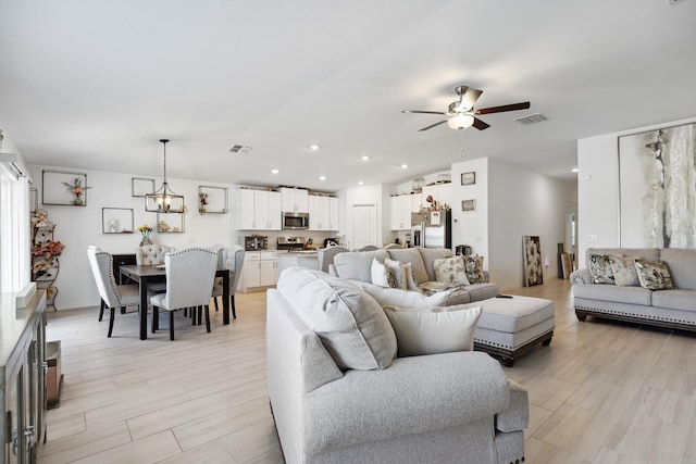 living area featuring ceiling fan with notable chandelier, visible vents, and recessed lighting