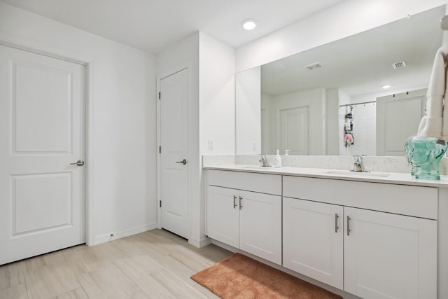 bathroom featuring double vanity, visible vents, baseboards, and a sink