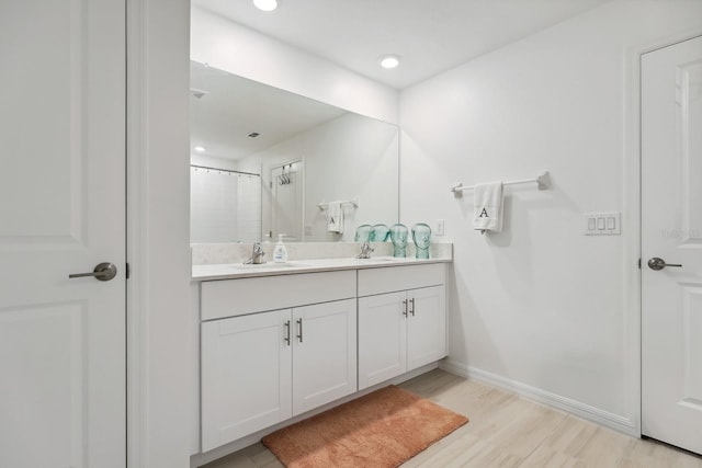 bathroom with a shower with curtain, double vanity, a sink, and wood finished floors
