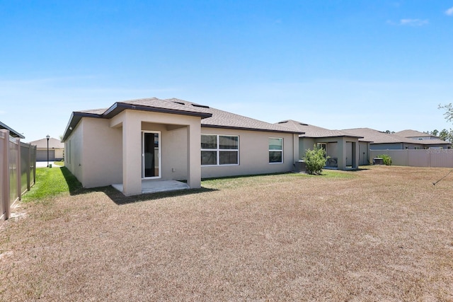 rear view of property with fence, stucco siding, and a lawn
