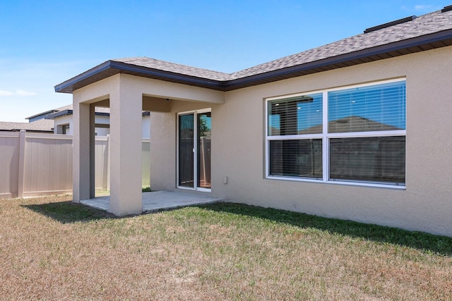 back of property featuring a lawn, a patio, fence, and stucco siding