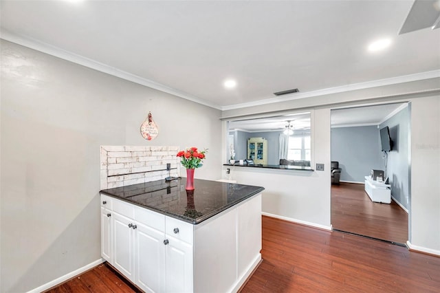 424 Forest Glen Ave, Lakeland, FL 33813 - kitchen featuring dark wood-style flooring, white cabinets, crown molding, a peninsula, and baseboards