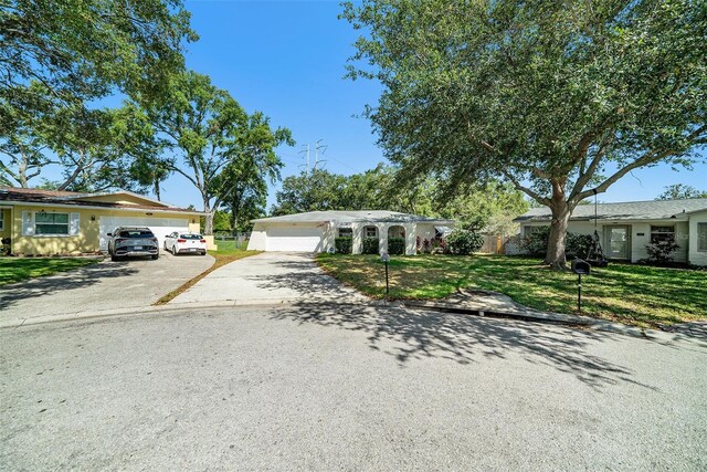 view of front facade featuring concrete driveway, a garage, fence, and a front lawn
