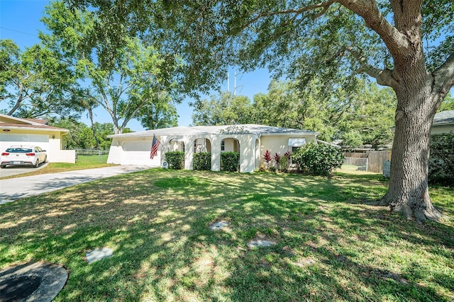 ranch-style home featuring stucco siding, fence, a front yard, and concrete driveway
