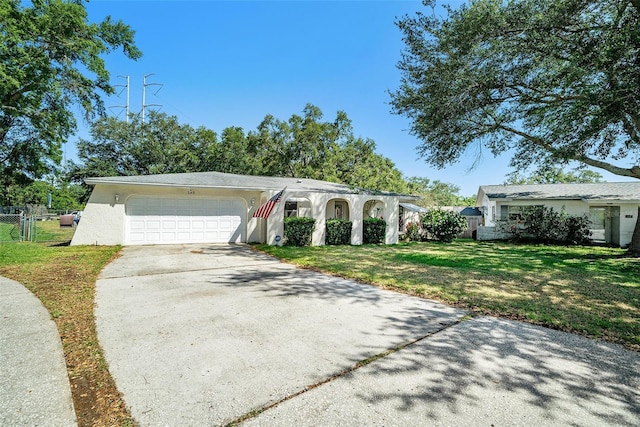 single story home with a garage, fence, a front yard, stucco siding, and driveway