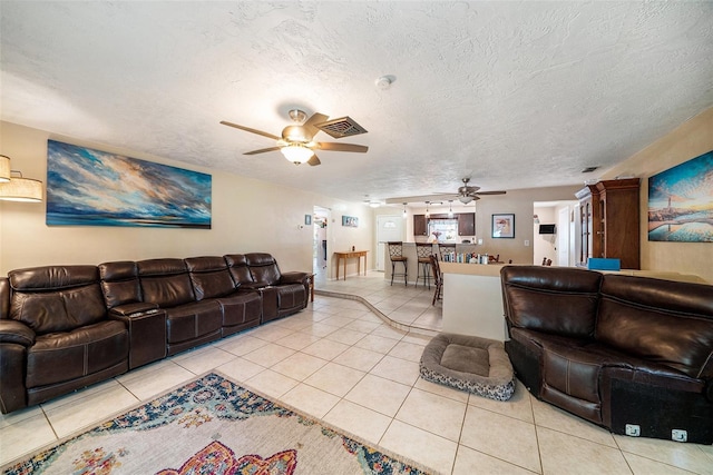 living area featuring a textured ceiling, ceiling fan, visible vents, and light tile patterned floors