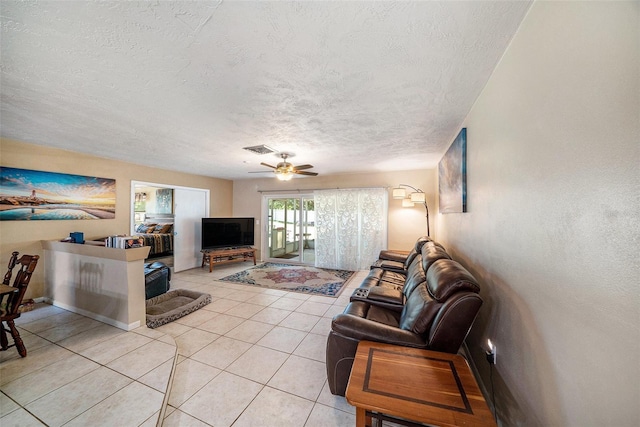living area featuring visible vents, a ceiling fan, a textured ceiling, and light tile patterned floors