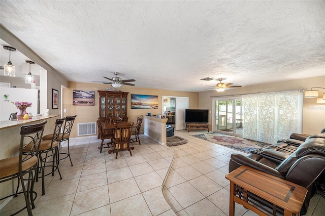 living area with a ceiling fan, a textured ceiling, visible vents, and light tile patterned floors