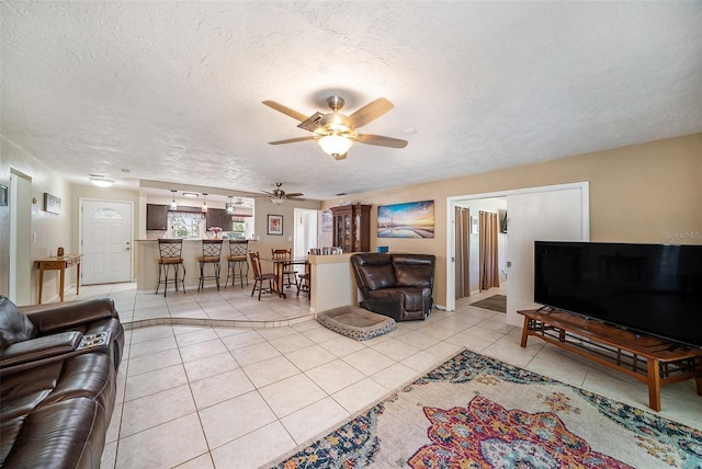living area with a textured ceiling, ceiling fan, and light tile patterned floors