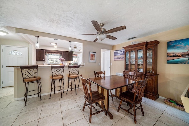 dining room with a textured ceiling, ceiling fan, visible vents, and light tile patterned floors
