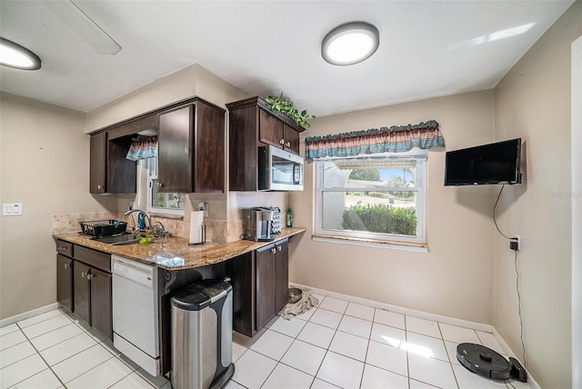 kitchen with dark brown cabinets, a sink, dishwasher, stainless steel microwave, and a wealth of natural light