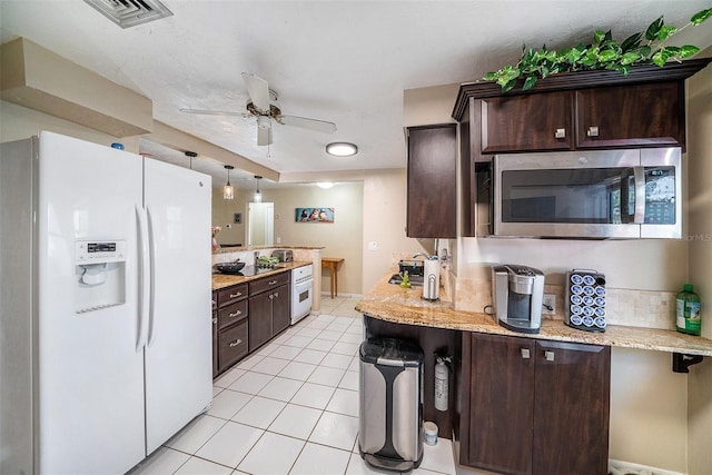 kitchen with dark brown cabinetry, visible vents, white refrigerator with ice dispenser, light tile patterned floors, and stainless steel microwave