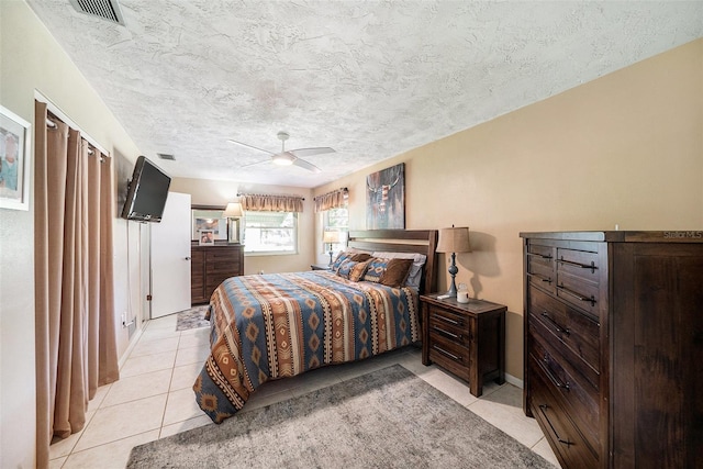 bedroom featuring light tile patterned floors, ceiling fan, a textured ceiling, and visible vents