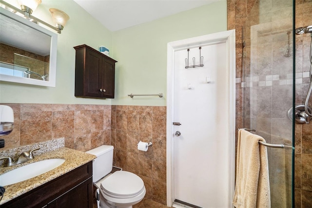 bathroom with vanity, tile walls, a shower stall, and toilet