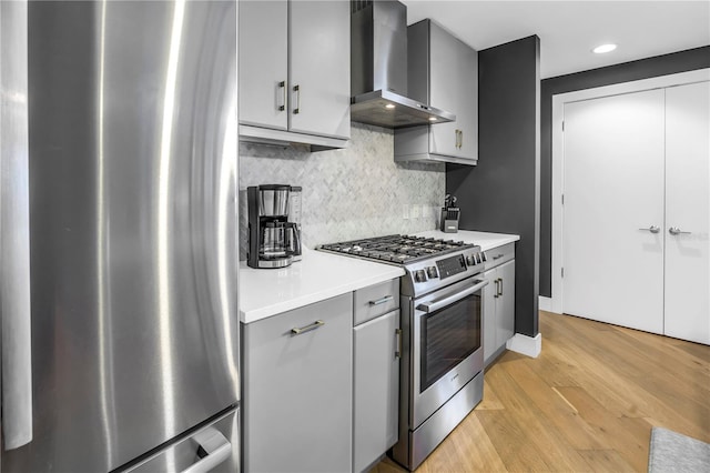 199 Dali Blvd Unit 902, Saint Petersburg, FL 33701 - kitchen featuring stainless steel appliances, wall chimney exhaust hood, gray cabinets, light wood finished floors, and decorative backsplash
