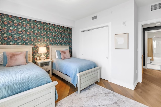 199 Dali Blvd Unit 902, Saint Petersburg, FL 33701 - bedroom featuring baseboards, a closet, wood finished floors, an accent wall, and wallpapered walls