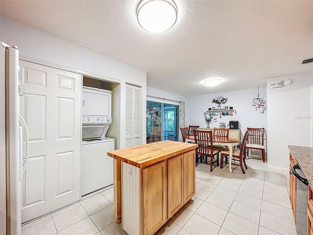 3078 Pointer Dr, Palm Harbor, FL 34683 - kitchen with wood counters, light tile patterned flooring, stacked washer / dryer, and fridge