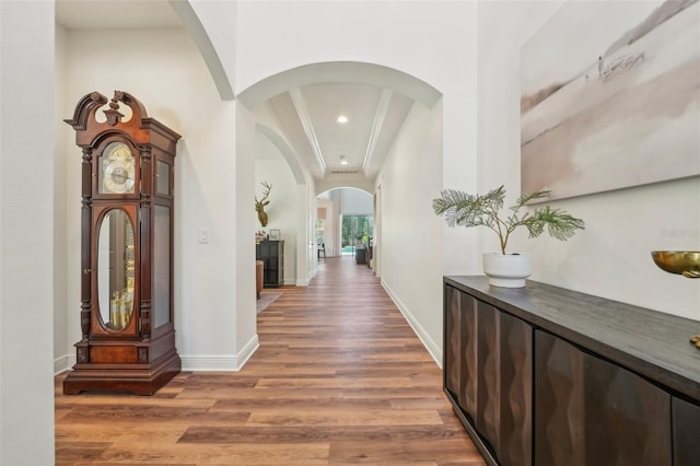 hallway with arched walkways, baseboards, recessed lighting, and wood finished floors