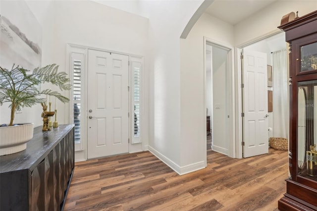 entryway featuring baseboards, arched walkways, and wood finished floors