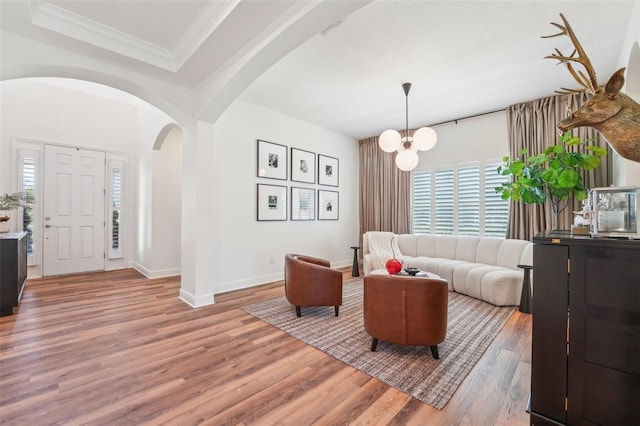 interior space featuring ornamental molding, wood finished floors, baseboards, a chandelier, and arched walkways