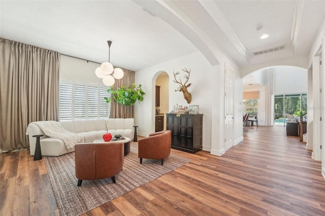 living area featuring visible vents, arched walkways, and wood finished floors