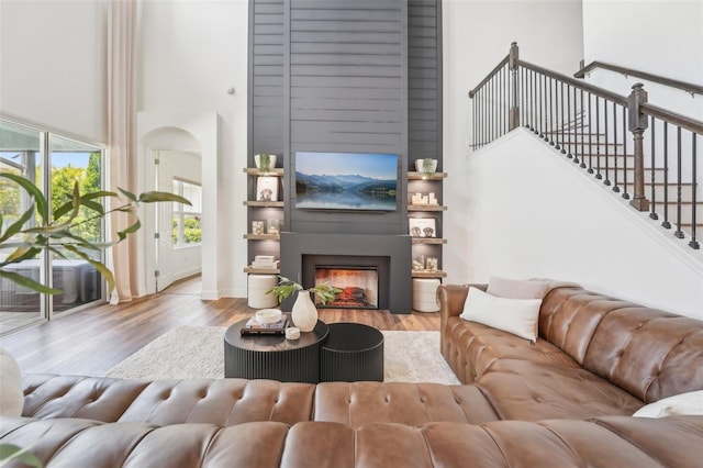 living room with baseboards, a large fireplace, wood finished floors, and a towering ceiling