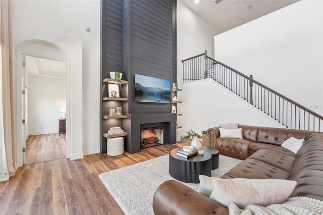 living area with wood finished floors, a fireplace, baseboards, a high ceiling, and stairway