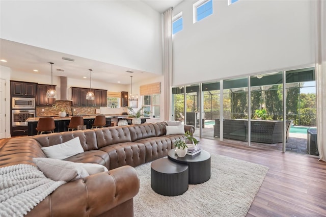 living room featuring recessed lighting, a high ceiling, and light wood-type flooring