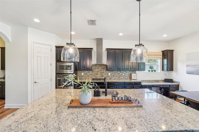 kitchen featuring wall chimney range hood, arched walkways, stainless steel appliances, wood finished floors, and visible vents