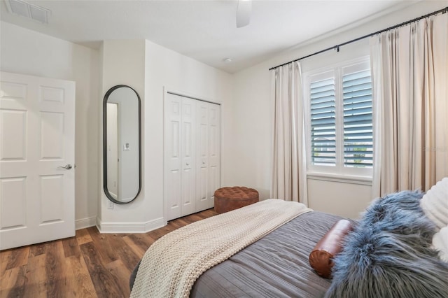 bedroom with ceiling fan, baseboards, wood finished floors, visible vents, and a closet