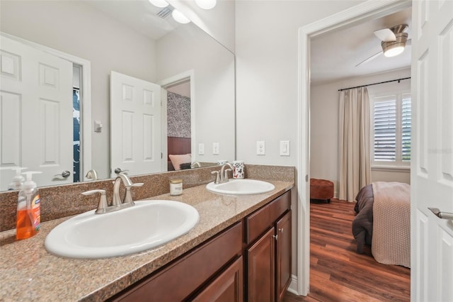 bathroom with a sink, ensuite bathroom, double vanity, and wood finished floors