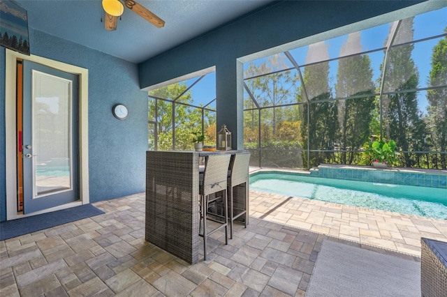 pool featuring outdoor dry bar, glass enclosure, ceiling fan, and a patio area