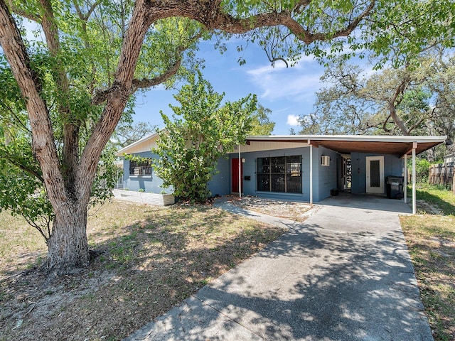 view of front facade with concrete driveway, fence, and a carport