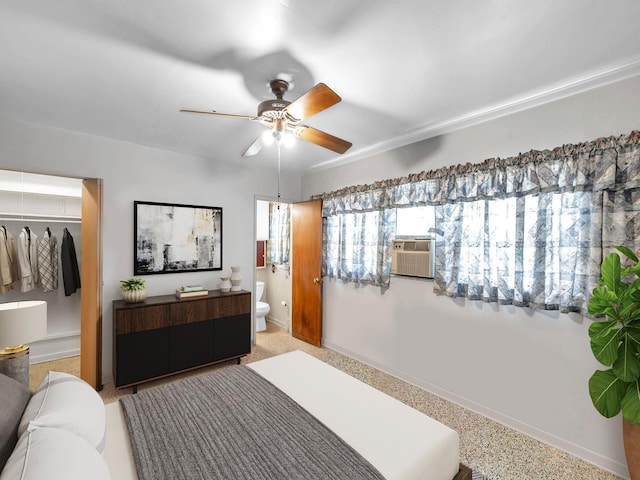 bedroom featuring baseboards, ceiling fan, ensuite bath, and cooling unit