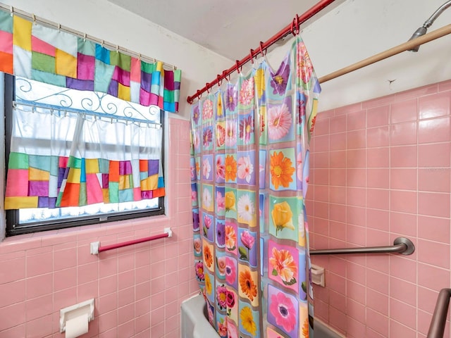 bathroom with tile walls and shower / bath combo