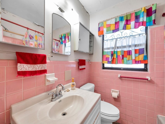 bathroom featuring vanity, wainscoting, toilet, and tile walls